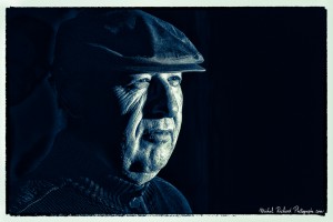 portrait d'homme à casquette au visage buriné en clair obscur et en noir et blanc -couleurs froides - portrait au flash par le photographe de portrait à Paris Michel Richard
